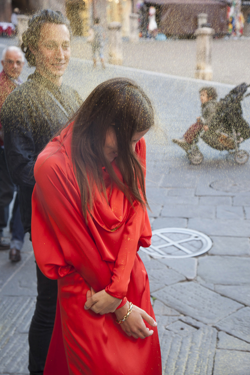 A la sortie de la cérémonie de mariage, un invité jette des glitters en riant sur la mariée, à Sienne, en Italie.