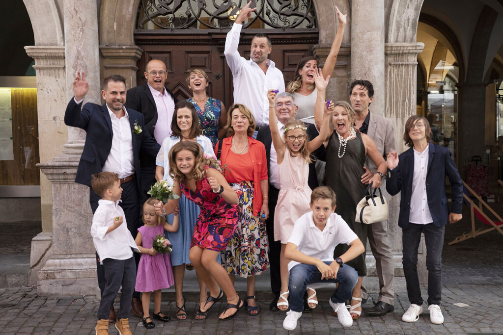 Photographie de groupe en mouvement après la cérémonie de mariage devant l'Hôtel de Ville de Lausanne.